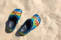 Colorful crocs footwear on the beach, vacation background. Colorful trendy croc beach shoes.